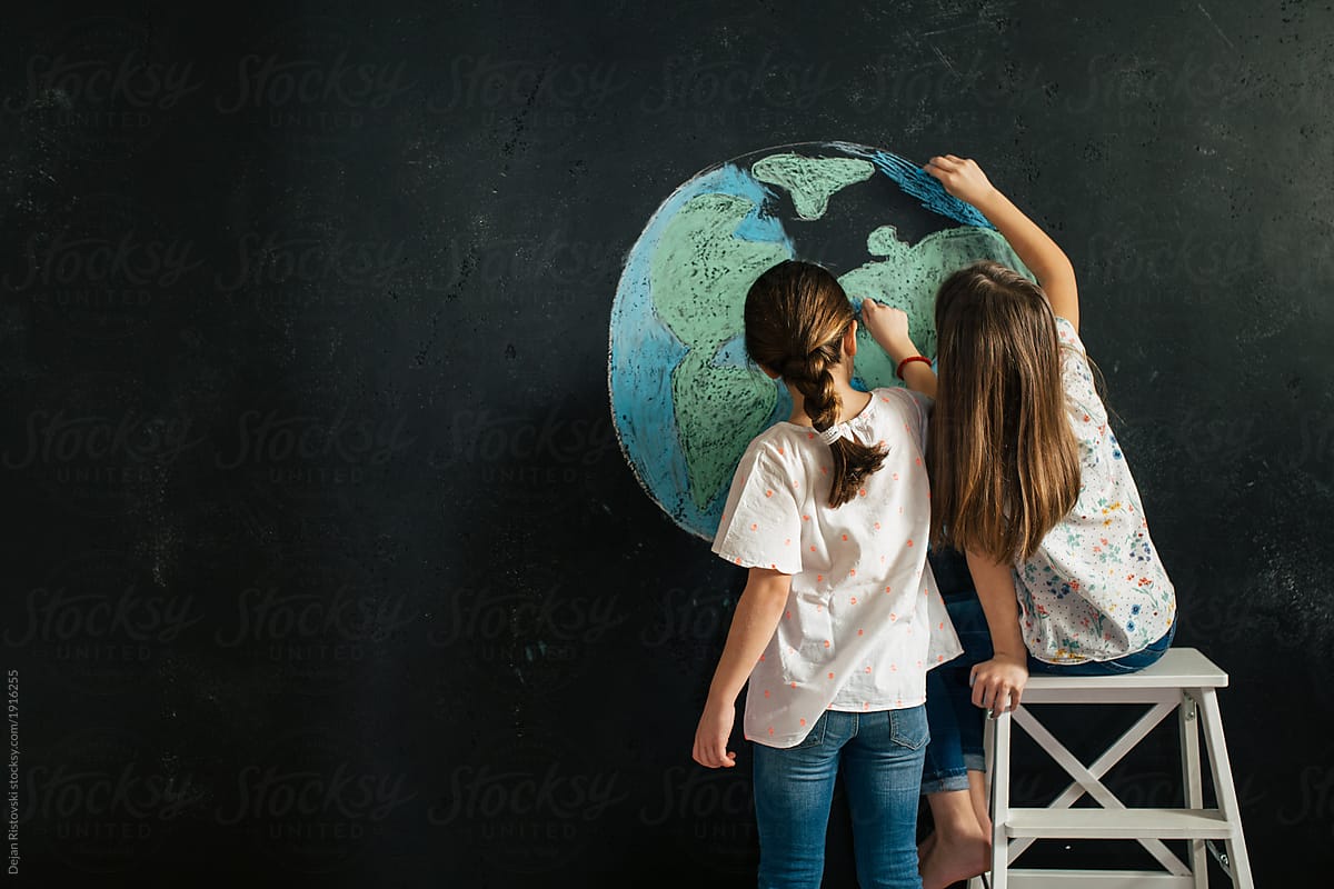 Young girls drawing planet earth on a blackboard