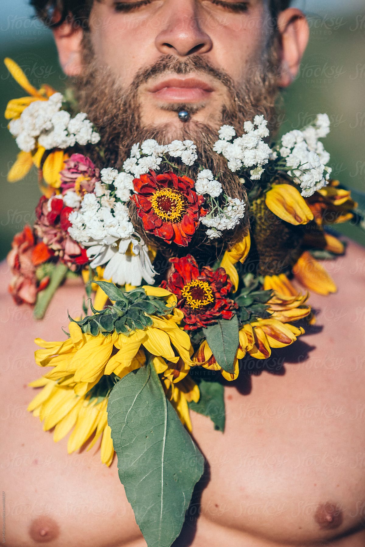 wild flowers,handsome hipster young man with colorful flowers in his beard enjoys the sun,summer