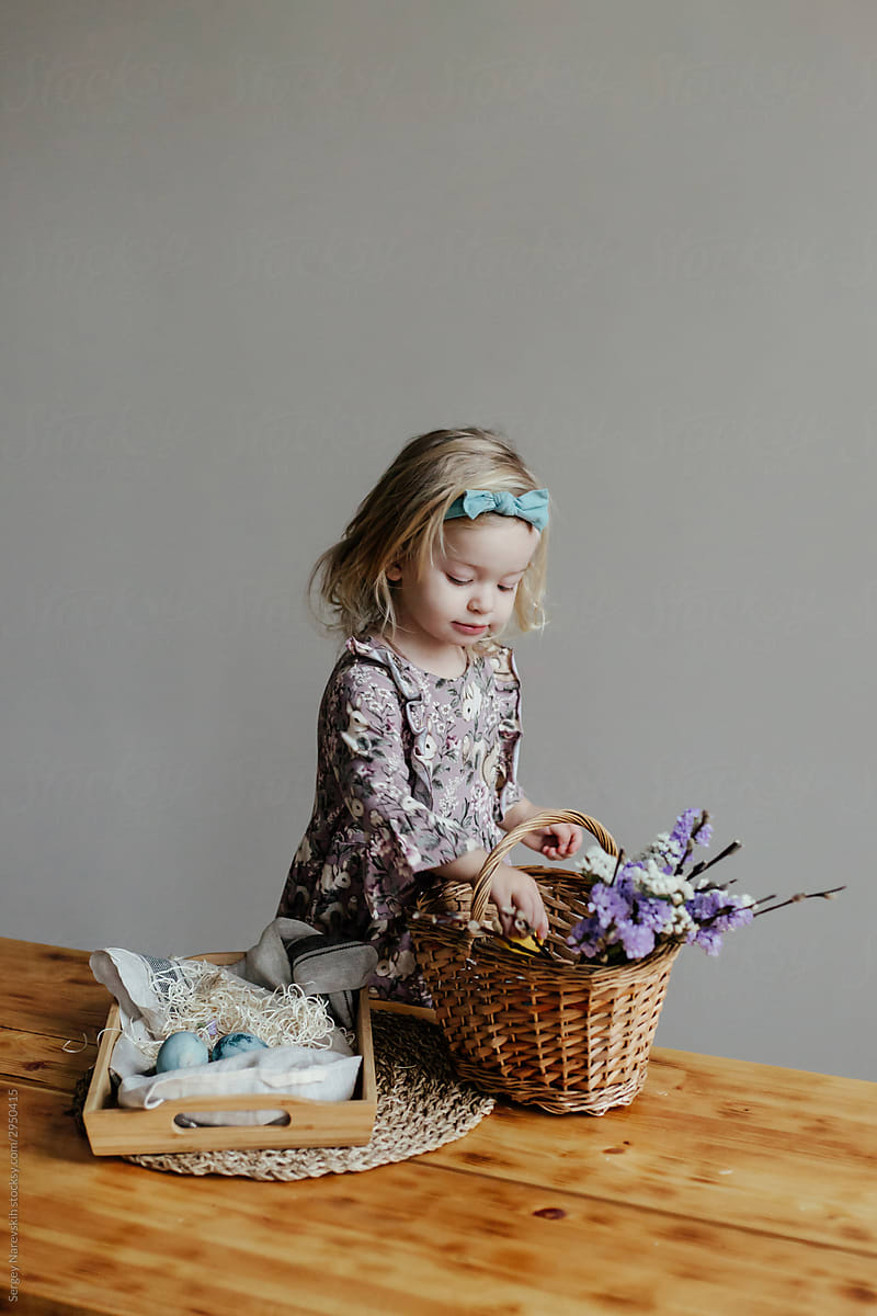 Little child preparing festive basket with eggs on Easter