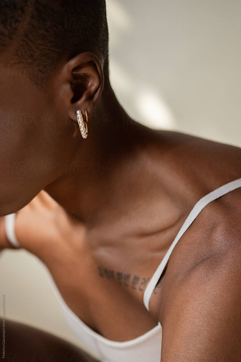 Black Woman Shoulder Detail With Korean Tattoo and Gold Earring