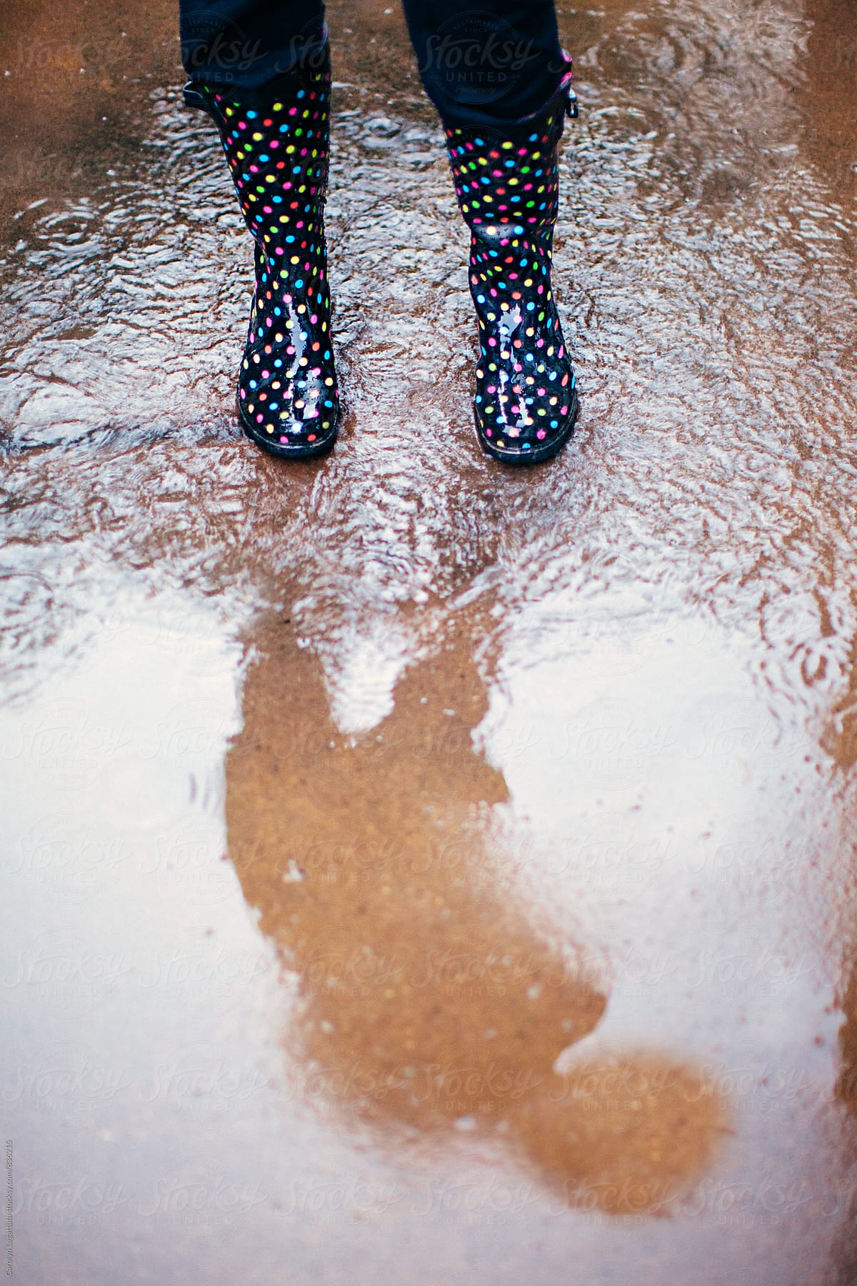 Rain boots splashing in a puddle with a shadow