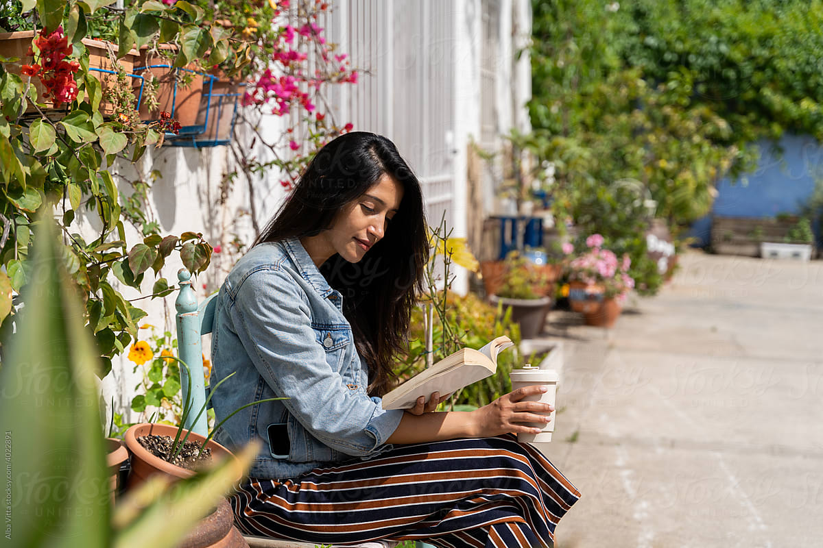 Happy woman in garden relaxing and reading a book