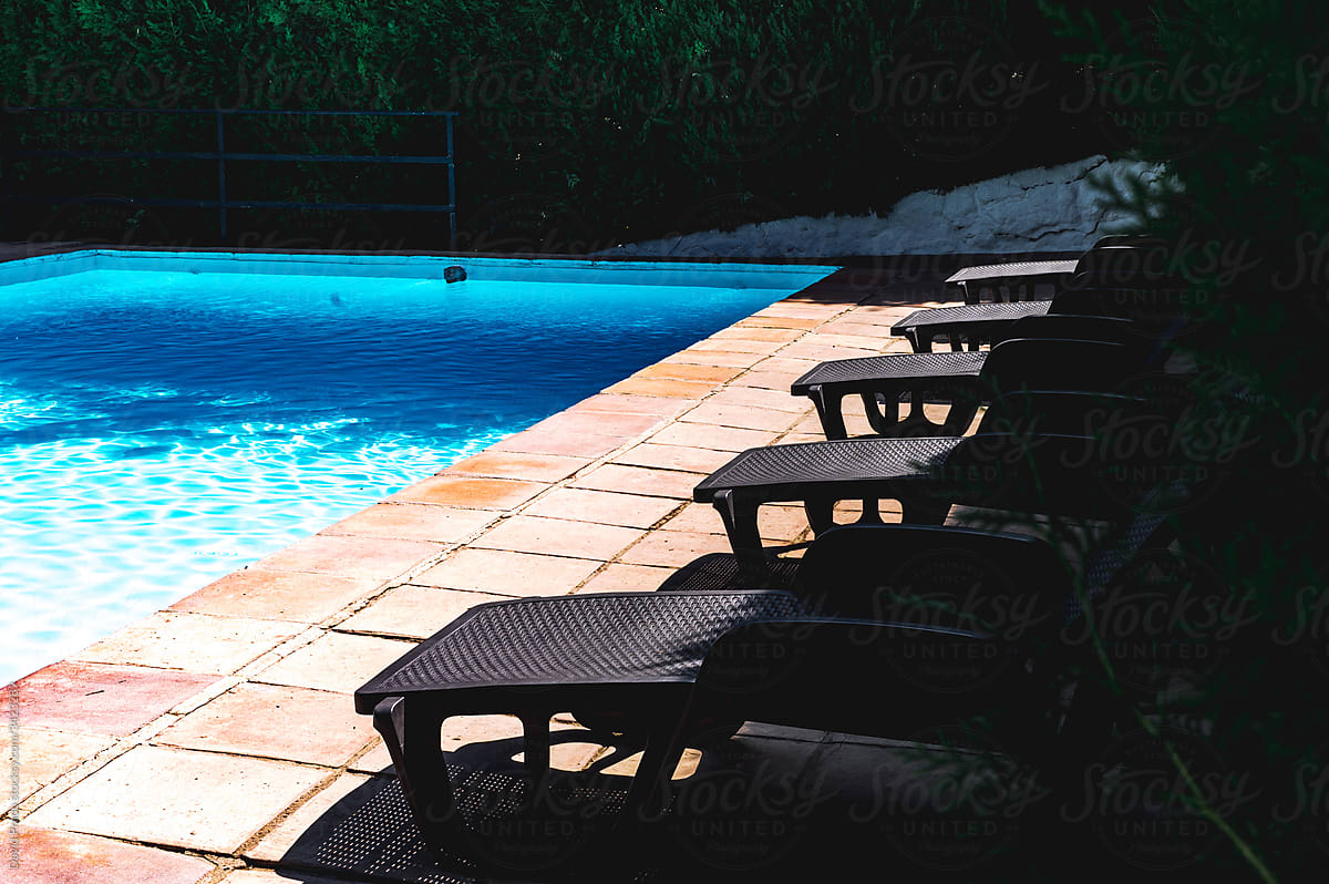 Loungers near swimming pool with blue water