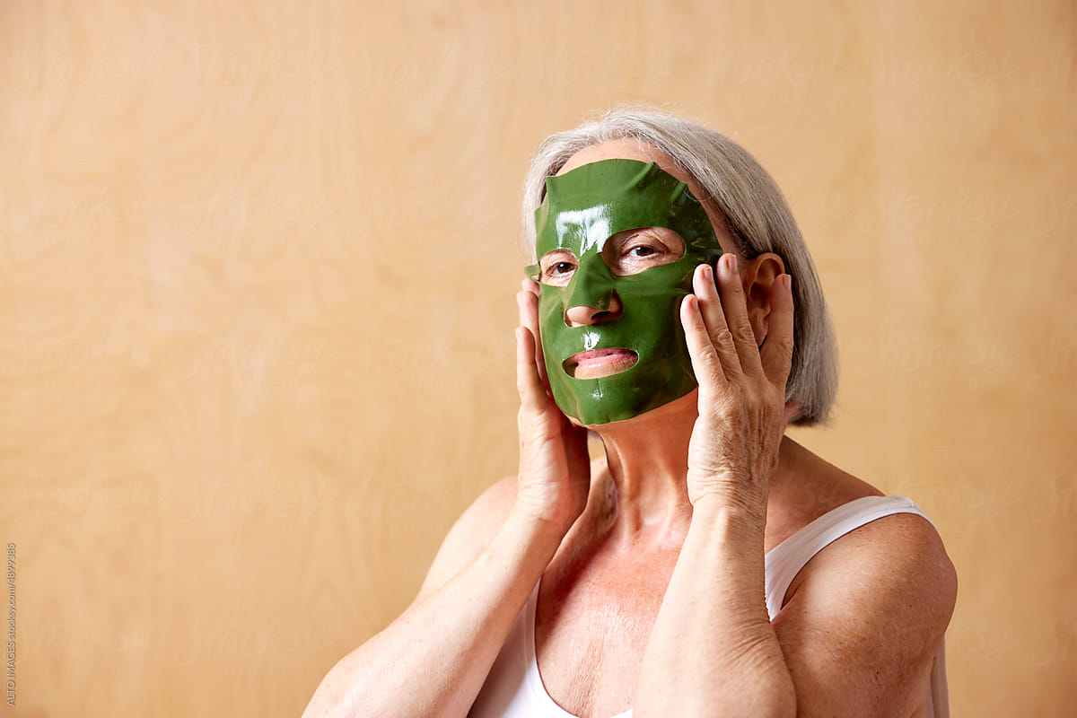 Senior woman applying sheet mask