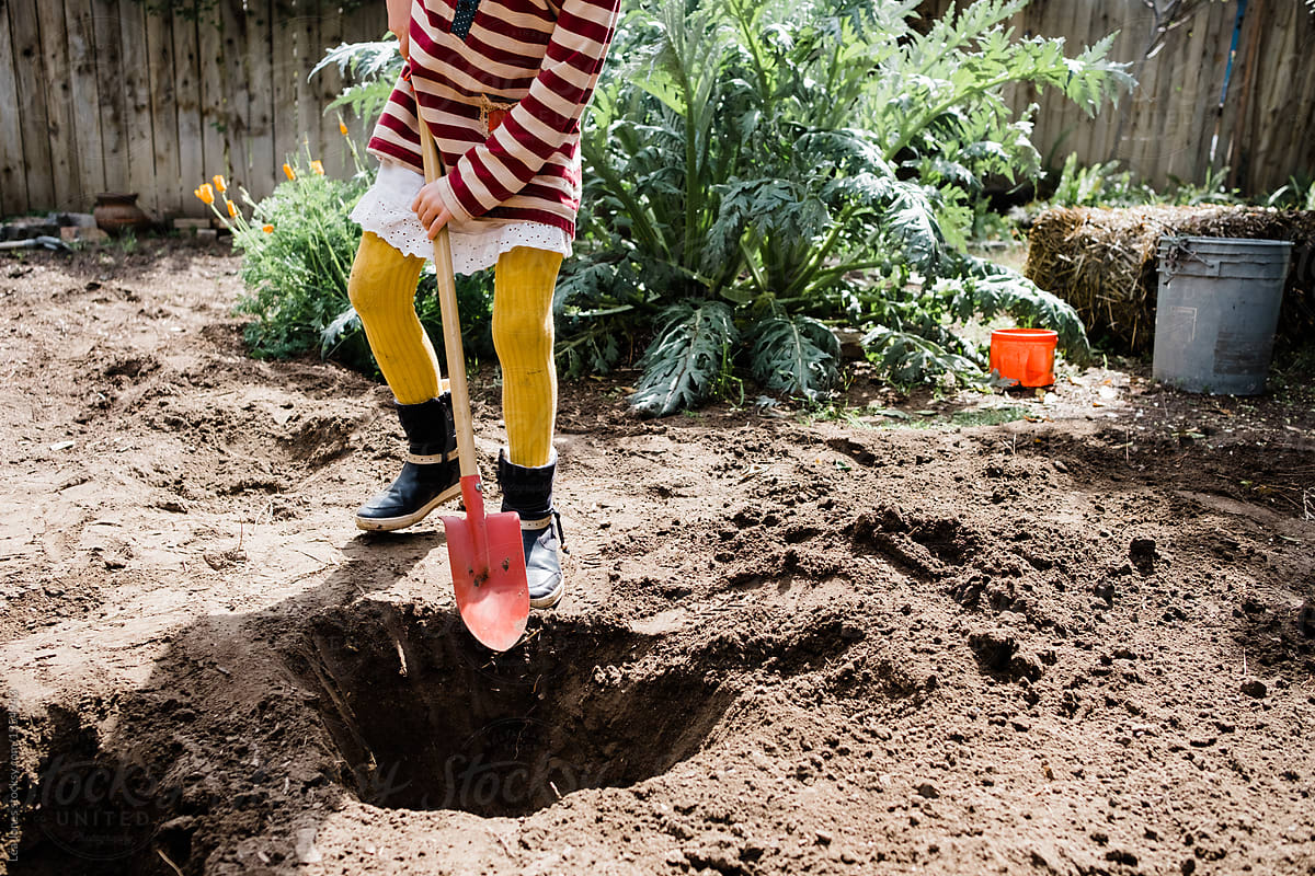 little girl  digging a big hole.