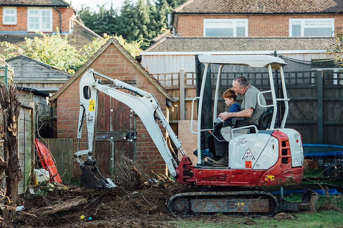 Wide of a father and son using a digger in their back garden