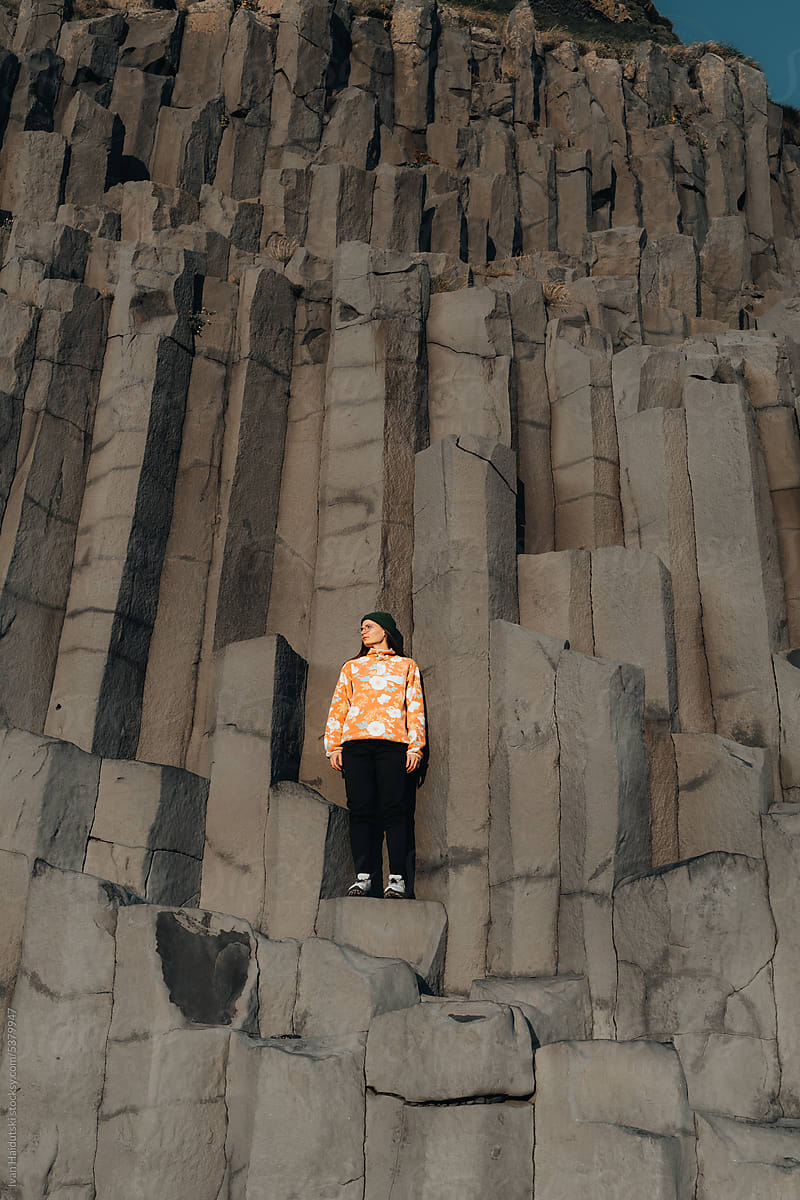 Woman standing on basalt columns in Iceland enjoying the big world