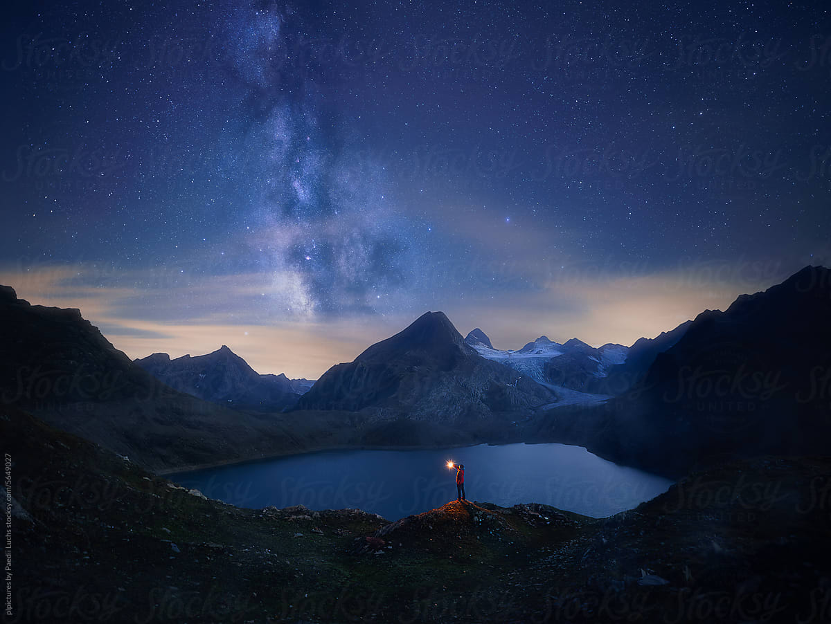 Adventurer standing at alpine lake under milky way night