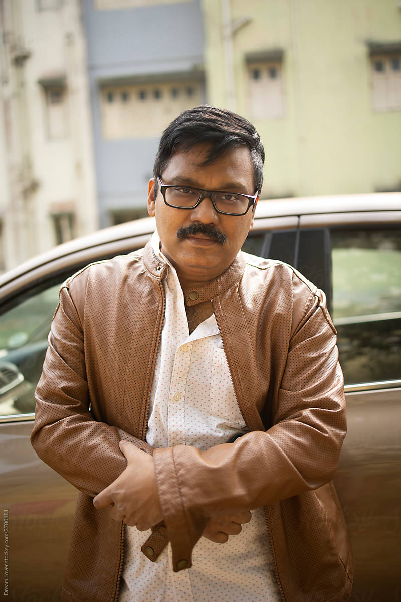 Middle aged Indian man wearing lather jacket and looking at camera at outdoors