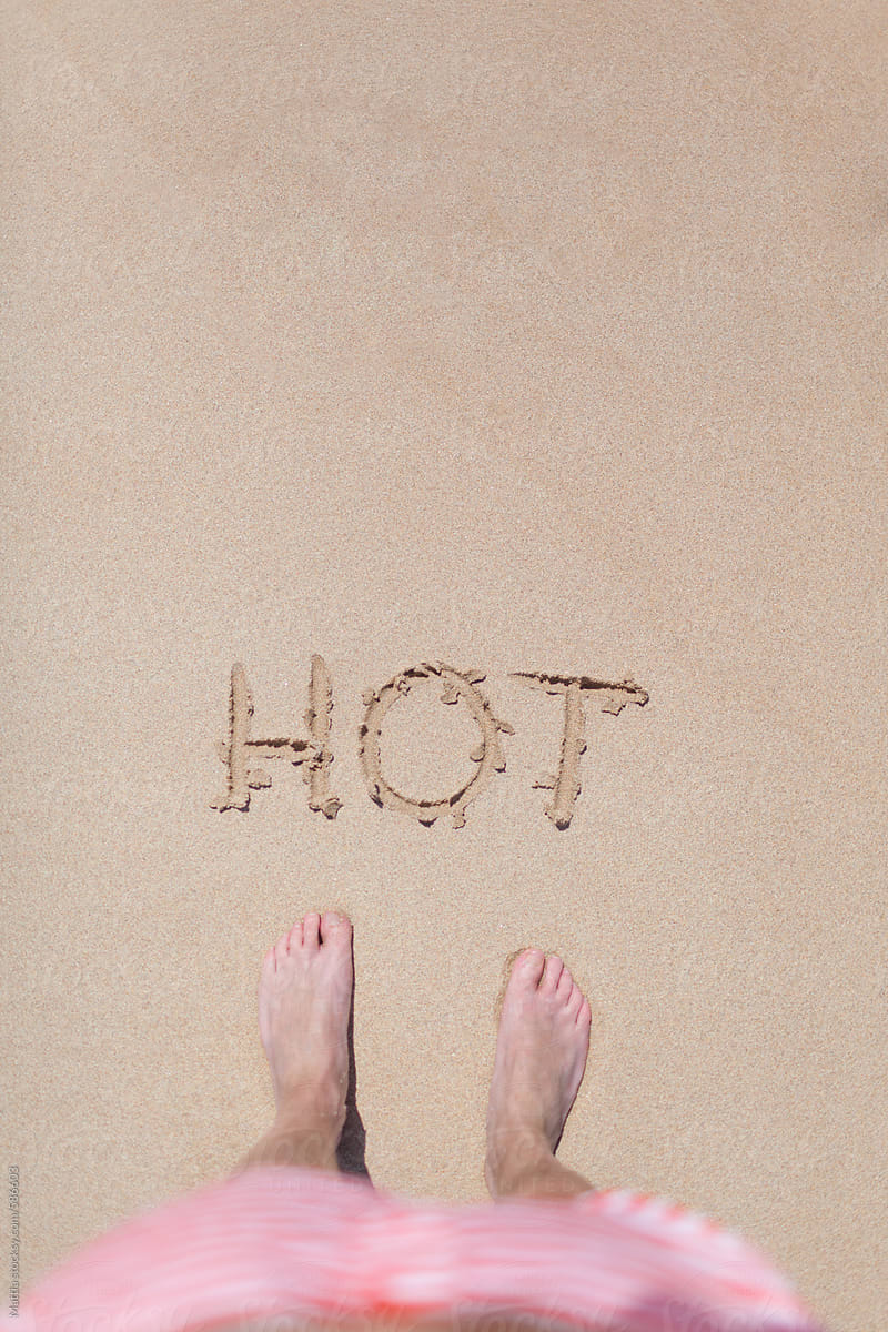 Hot Written on a Sandy Beach . Visible Feet