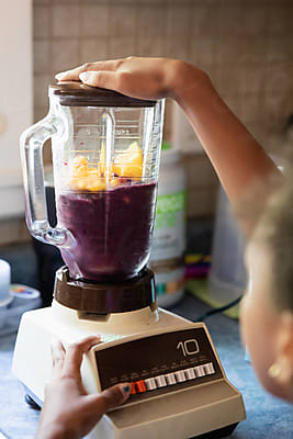 Young Girl Pouring Frozen Fruit Into A Blender by Stocksy Contributor  Anya Brewley Schultheiss - Stocksy