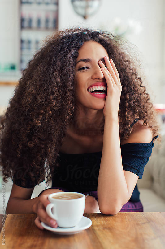 Portrait Of A Happy Curly Woman Having Coffee In A Restaurant By 
