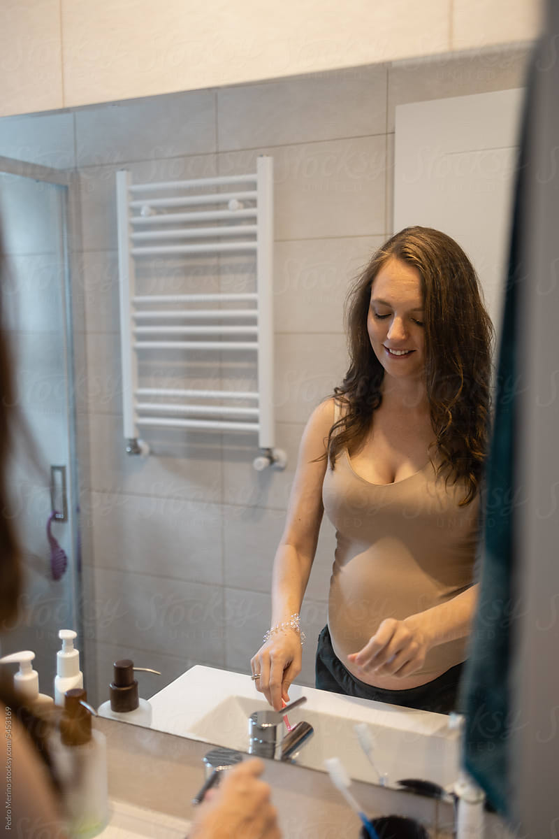 Pregnant woman brushing her teeth in the bathroom at home