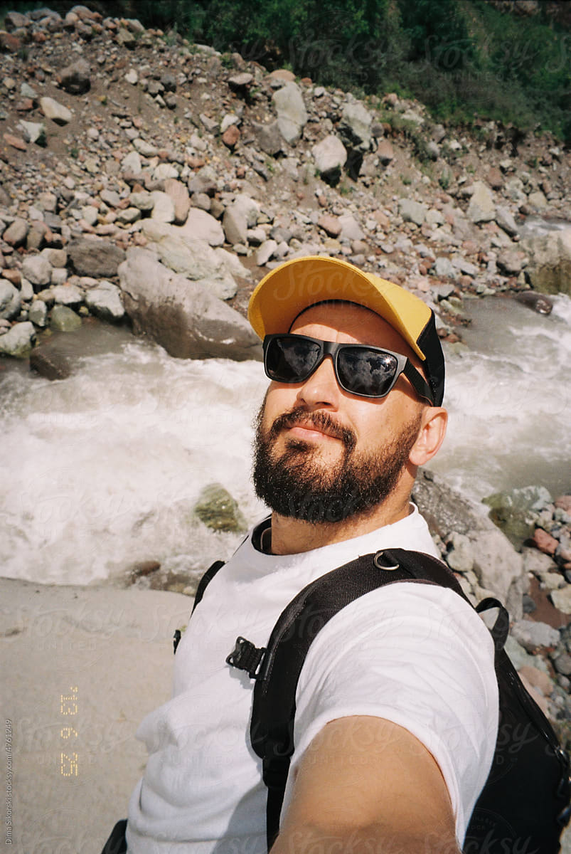 Bearded traveler took a selfie on a film camera in the mountains