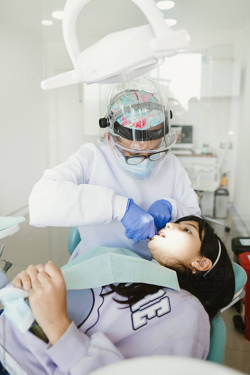 Female dentist adjusting braces to patient
