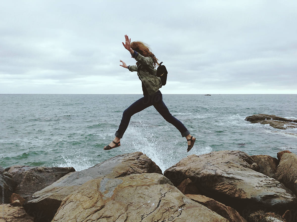 Woman Jumping On Jetty Rocks By Stocksy Contributor Kevin Russ Stocksy