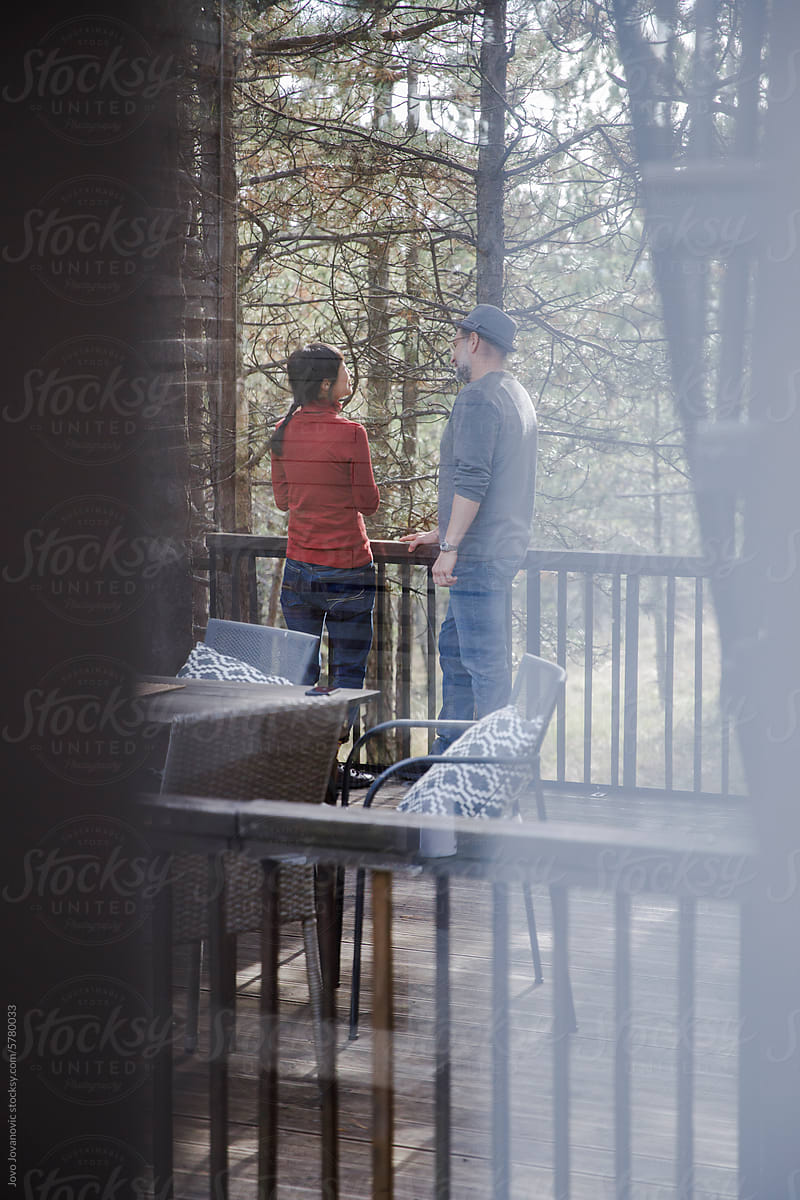 Couple talking in balcony seen through glass window