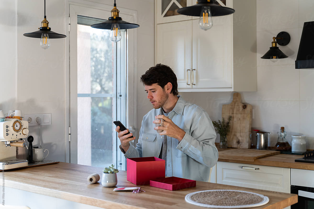 Young man using smartphone in kitchen
