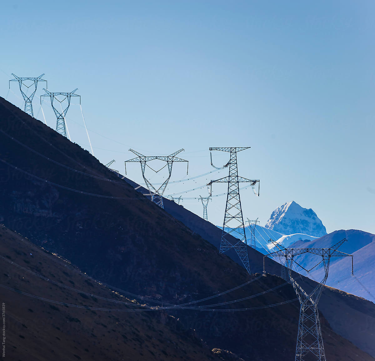 Green energy sources transmission tower and snow mountain