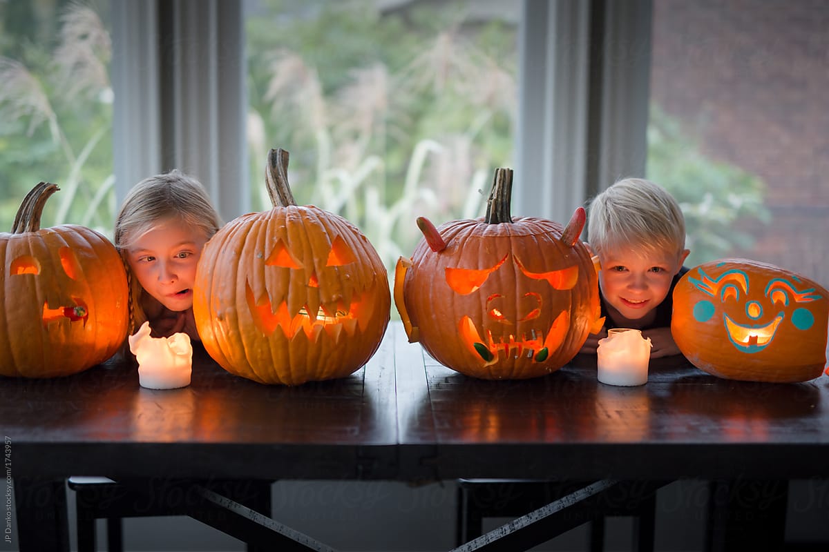 Sister and brother display their Halloween jack-o-lanterns and m