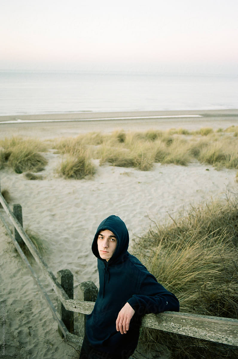 Portrait of pensive man in a hoodie on the beach