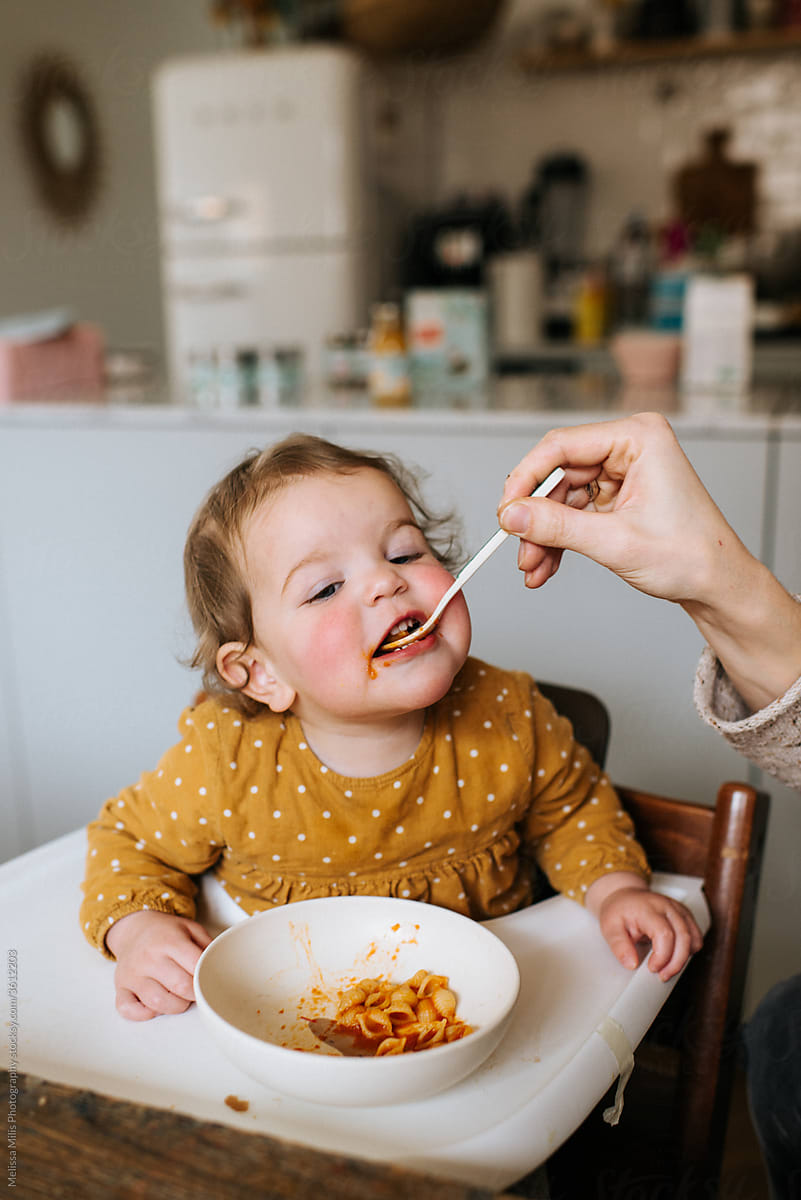 Baby Girl With Polkadot Dress Eating Pasta In A High Chair by Stocksy  Contributor Melissa Milis Photography - Stocksy