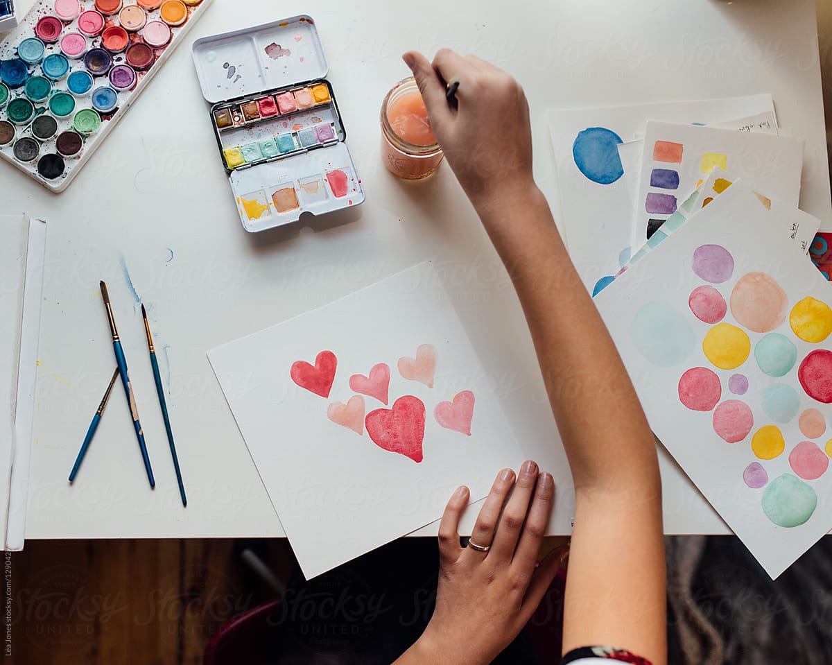 stock photo of teen painting pink hearts in watercolours