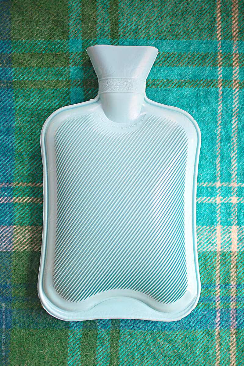 blue hot water bottle sitting on green check blanket