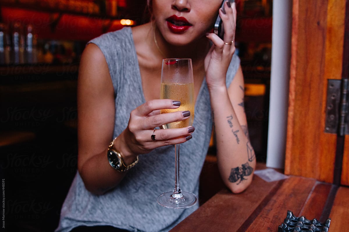 Young female asian model talks on phone and drinks champagne