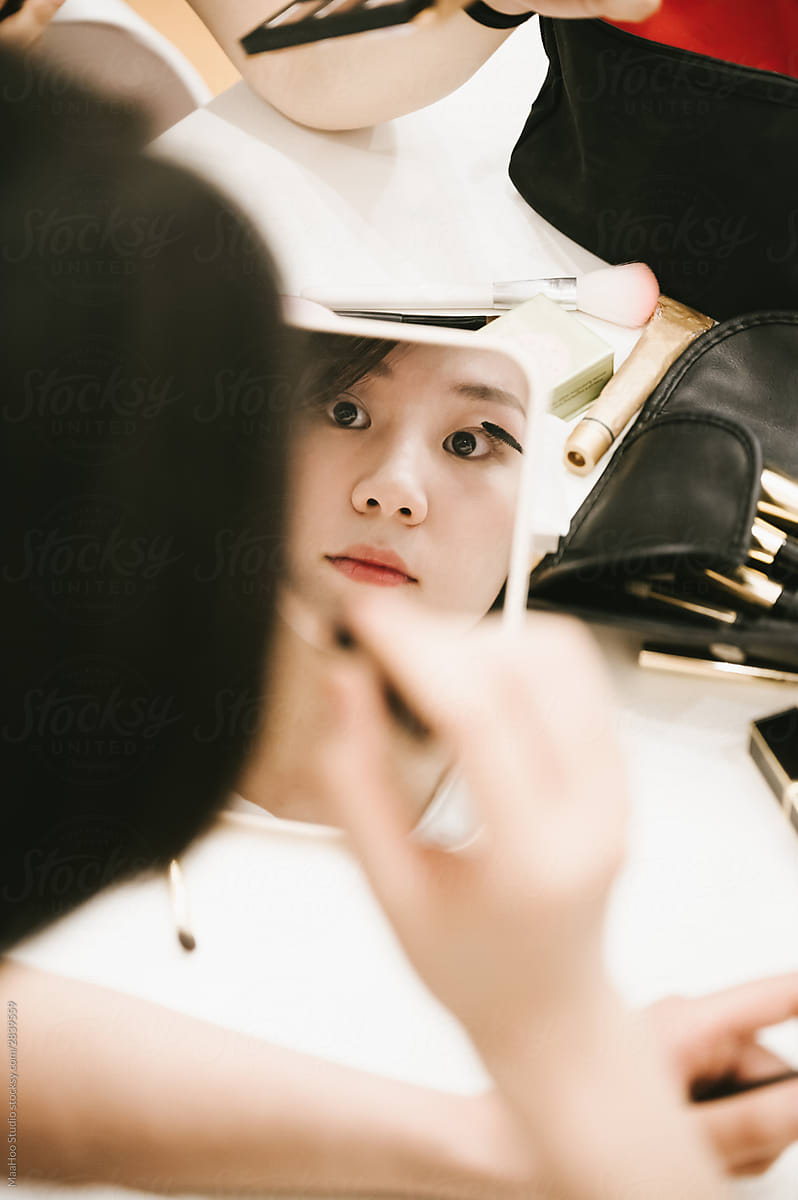 Young woman applying mascara in mirror