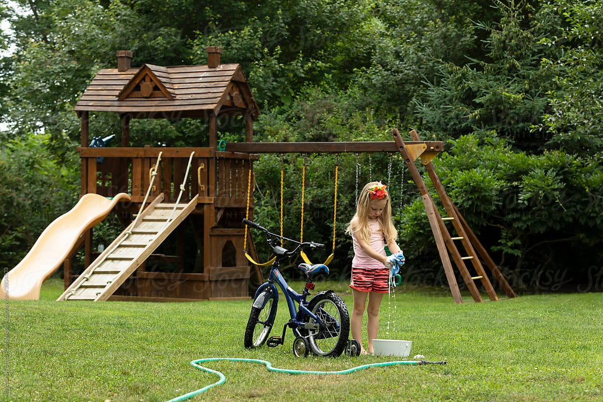 Young girl Washing her bicycle in the backyard of suburban home
