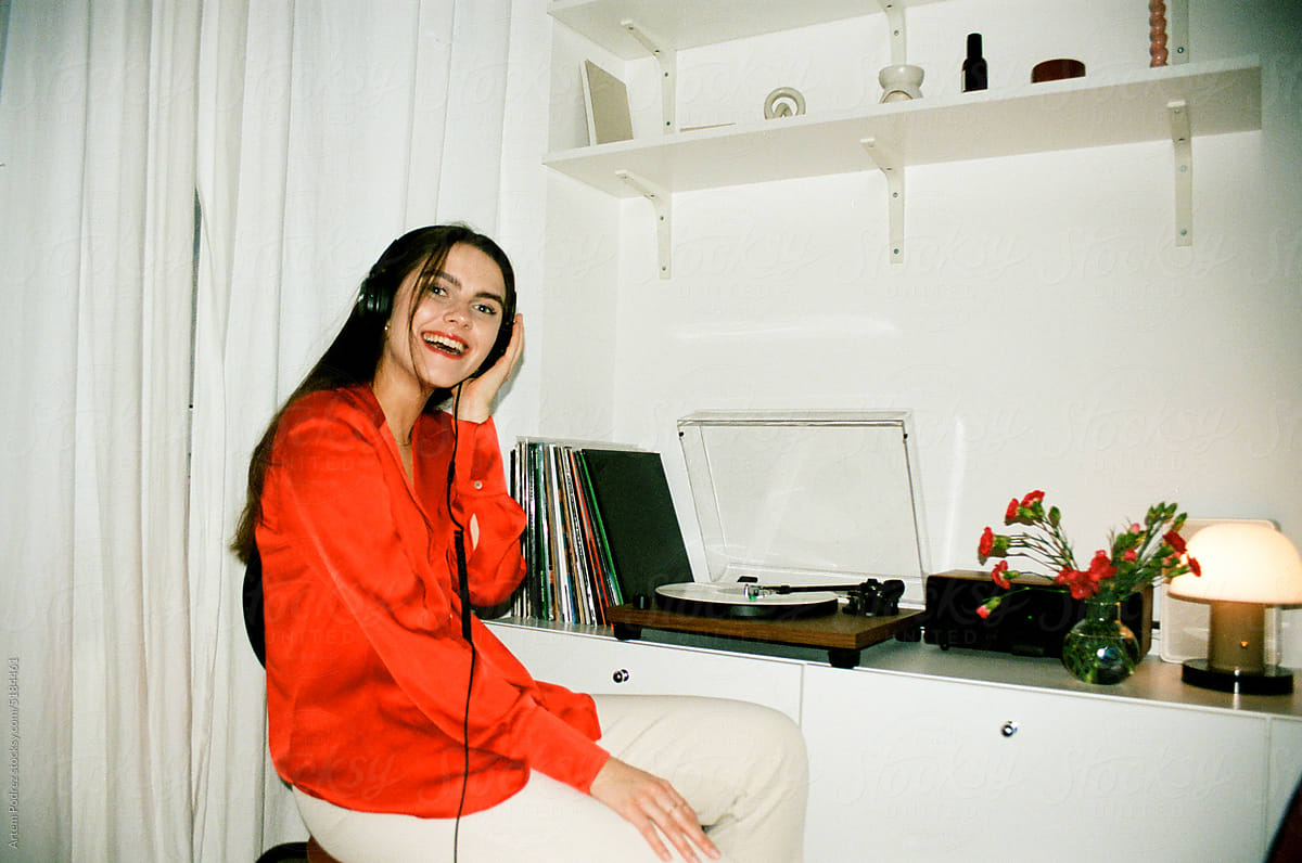 Film photo woman in a red shirt listens to music on a turntable