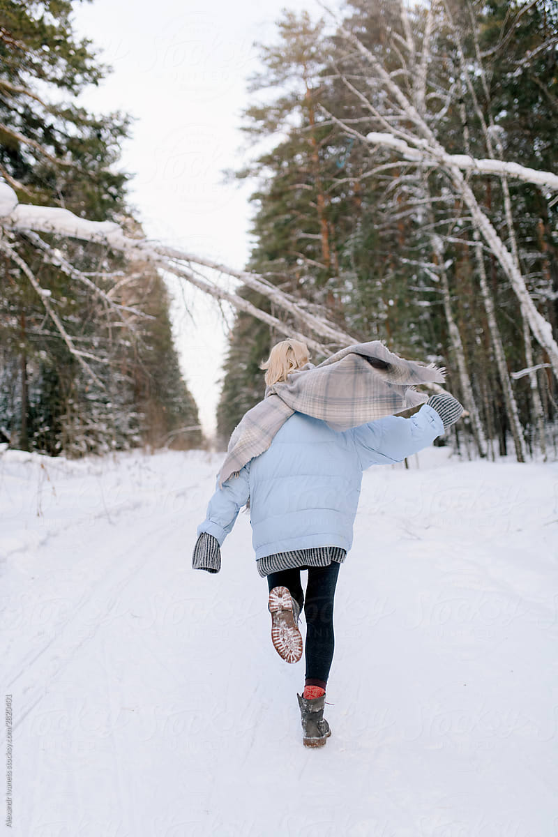 Unrecognizable woman running in snowy forest