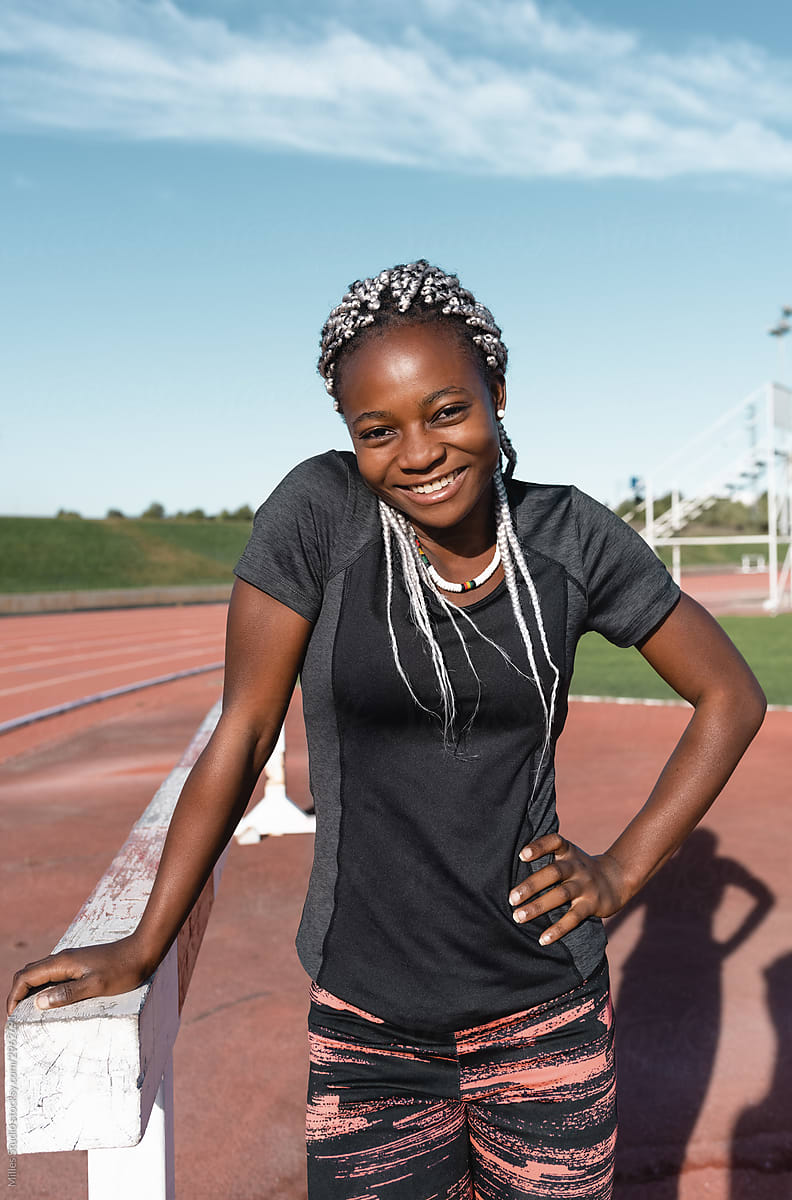 Cheerful black athlete near barrier