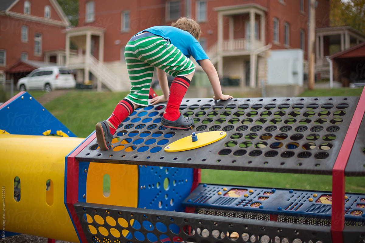 Boy in colorful clothing climbing on play structure
