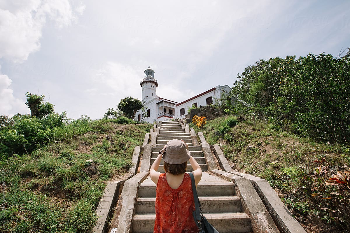 A lady tourist takes a souvenir photo of a lighthouse built during the Spanish colonial period