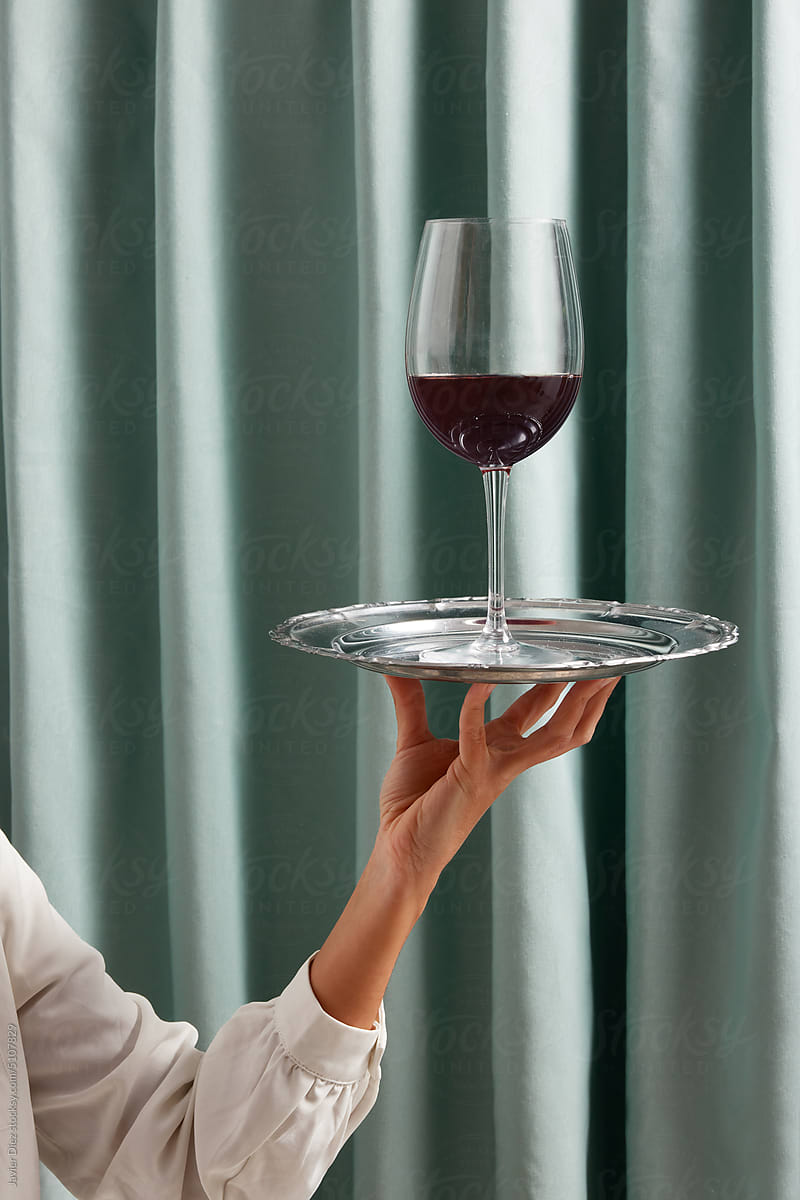 Crop waiter with wineglass on tray