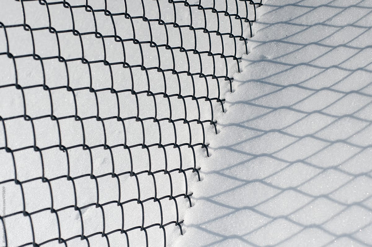 Abstracted fence with shadow on snow-covered surface