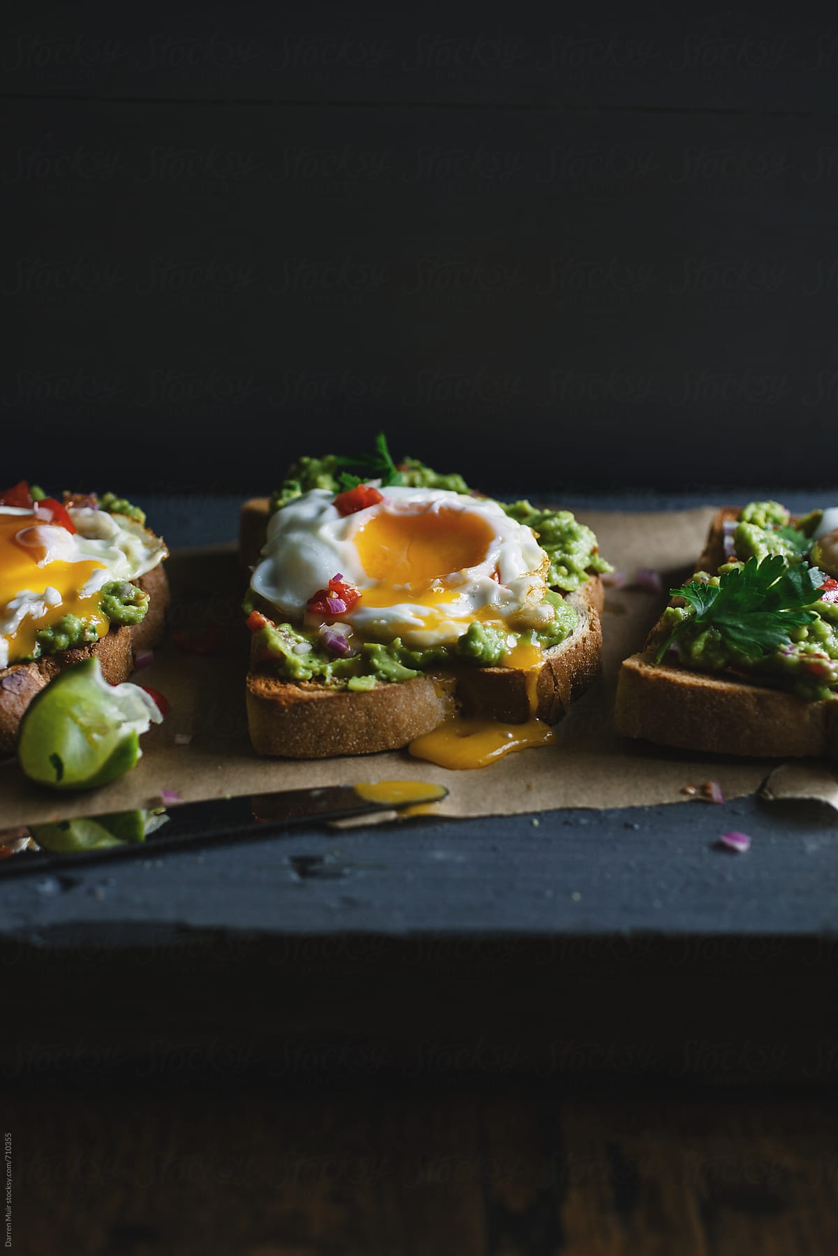 Avocado and fried egg toasts on a table.