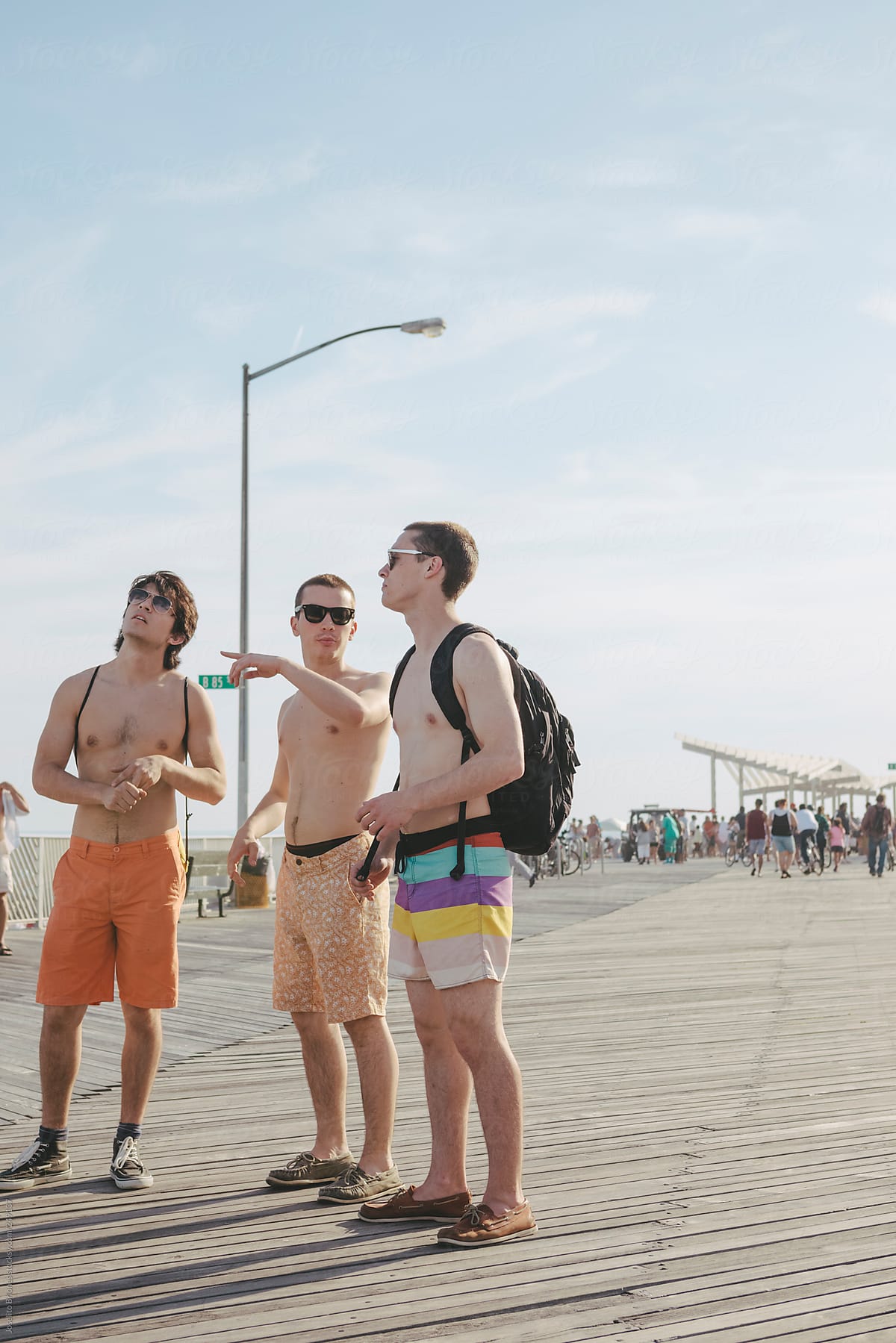 Young Men Friends Hanging Out in Rockaway Beach Boardwalk on a Hot Summer Day