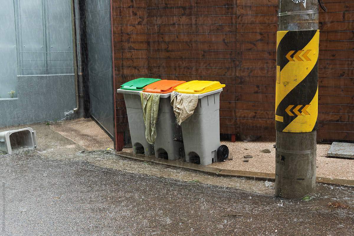 Colorful trash bins with heavy rain on the street