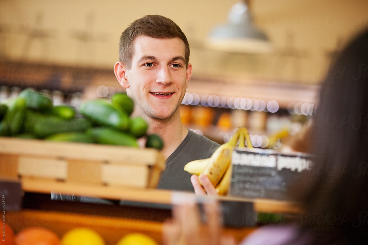 Market: Young Man Flirts With Woman In Produce Area