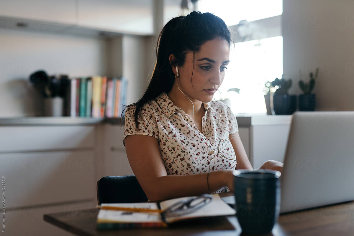 Young woman in earbuds at laptop