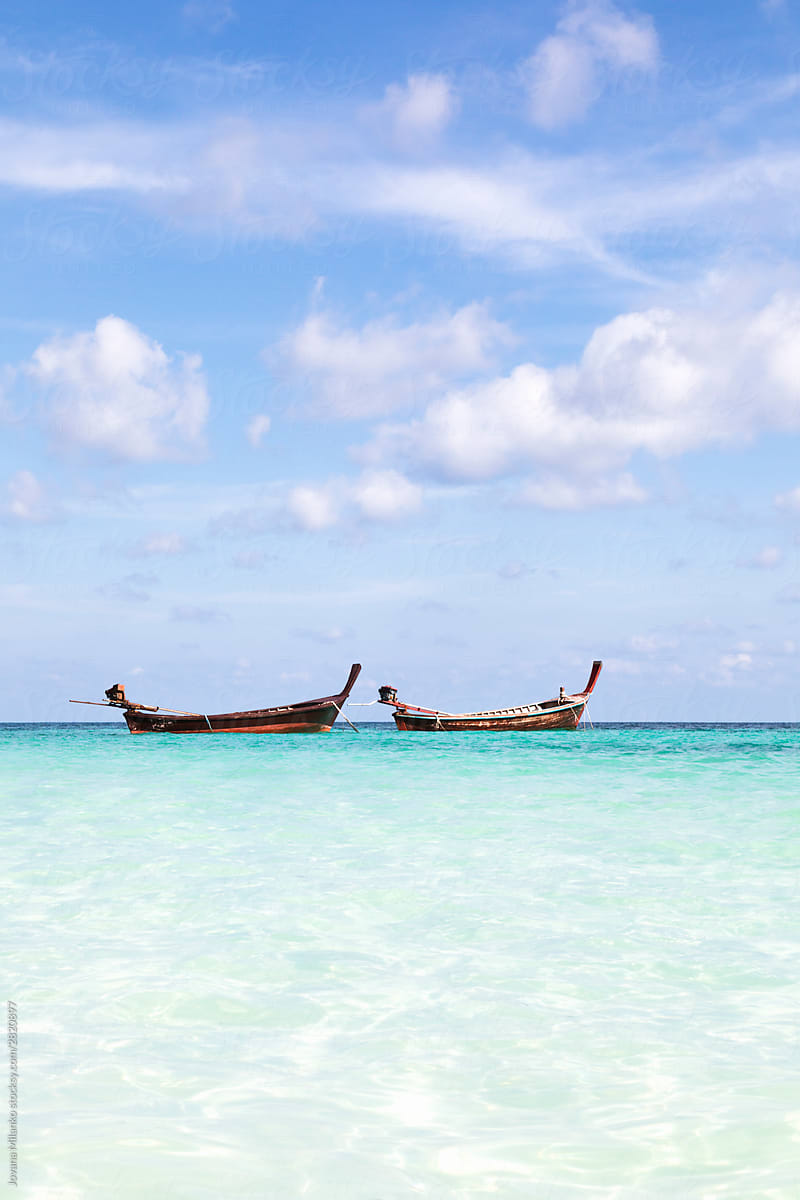 Two long tail boats floating on turquoise sea