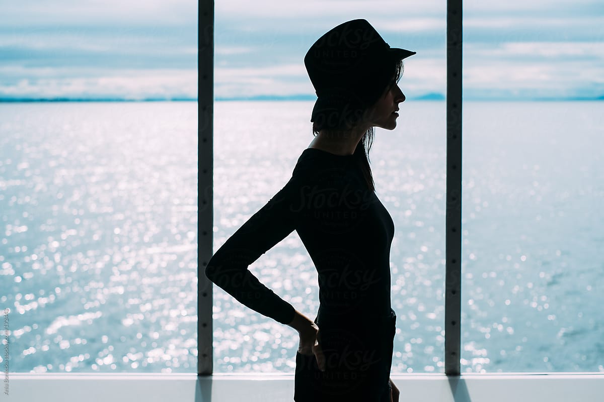Silhouette of a woman standing in front of a window facing the ocean