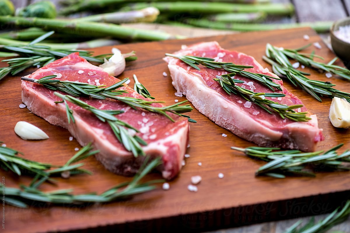 Raw Sirloin Steaks with Rosemary on Cutting Board