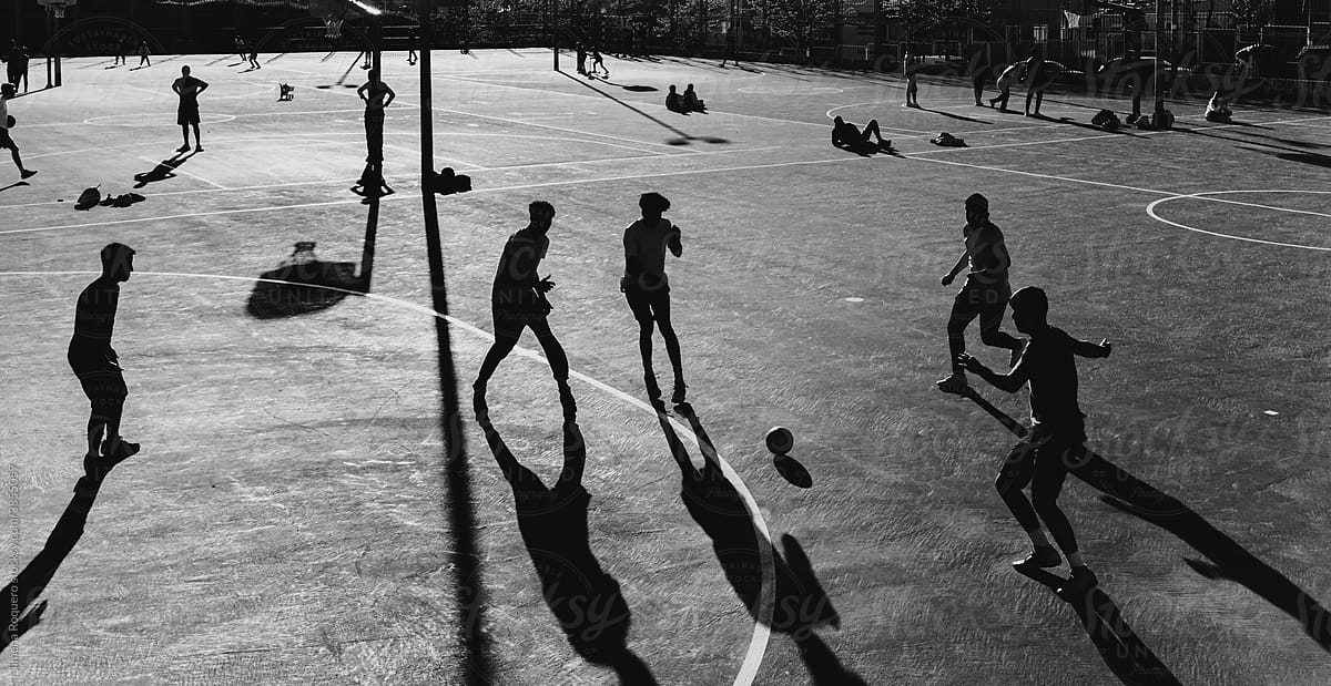 Black and white far view of urban soccer field with a group of people playing