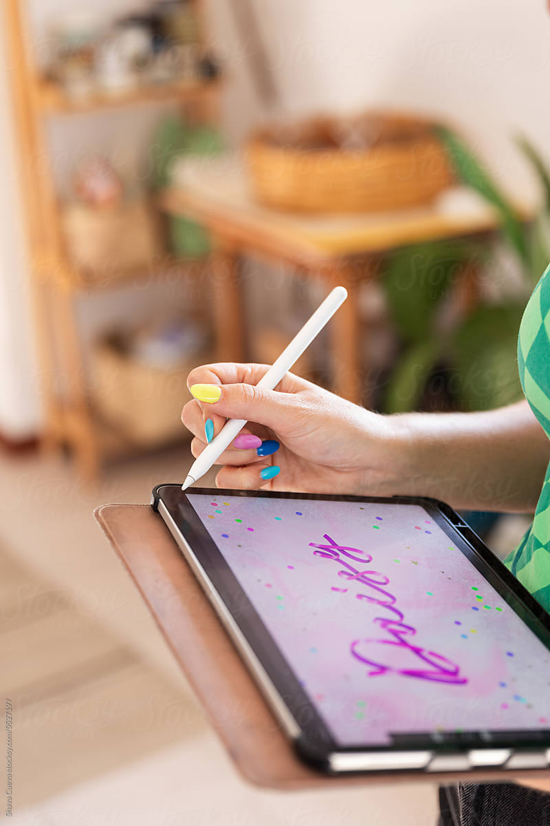 An anonymous graphic designer designing on a tablet a pink typeface