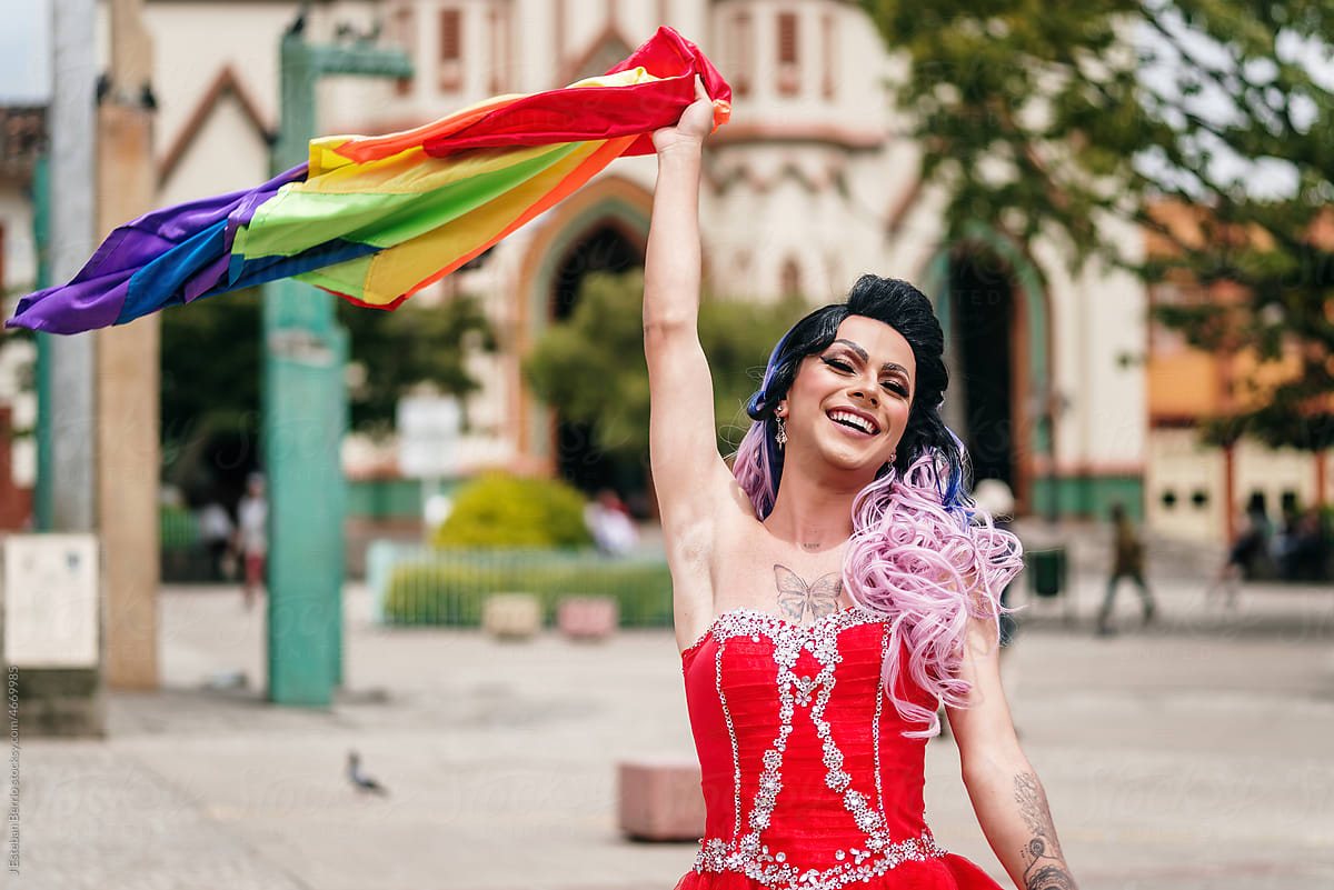 Latino drag queen raising the lgbt flag.
