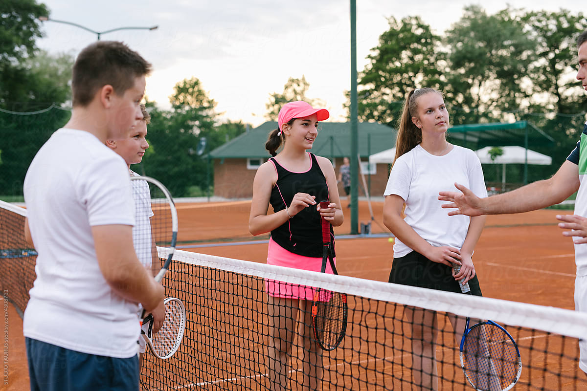 Coach teaching kids the rules of the tennis